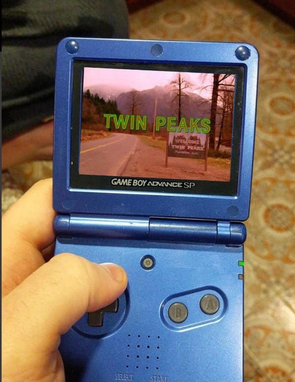 Game Boy Advance SP showing the Welcome to Twin Peaks sign. Nostalgic tech joke about watching shows on retro consoles.