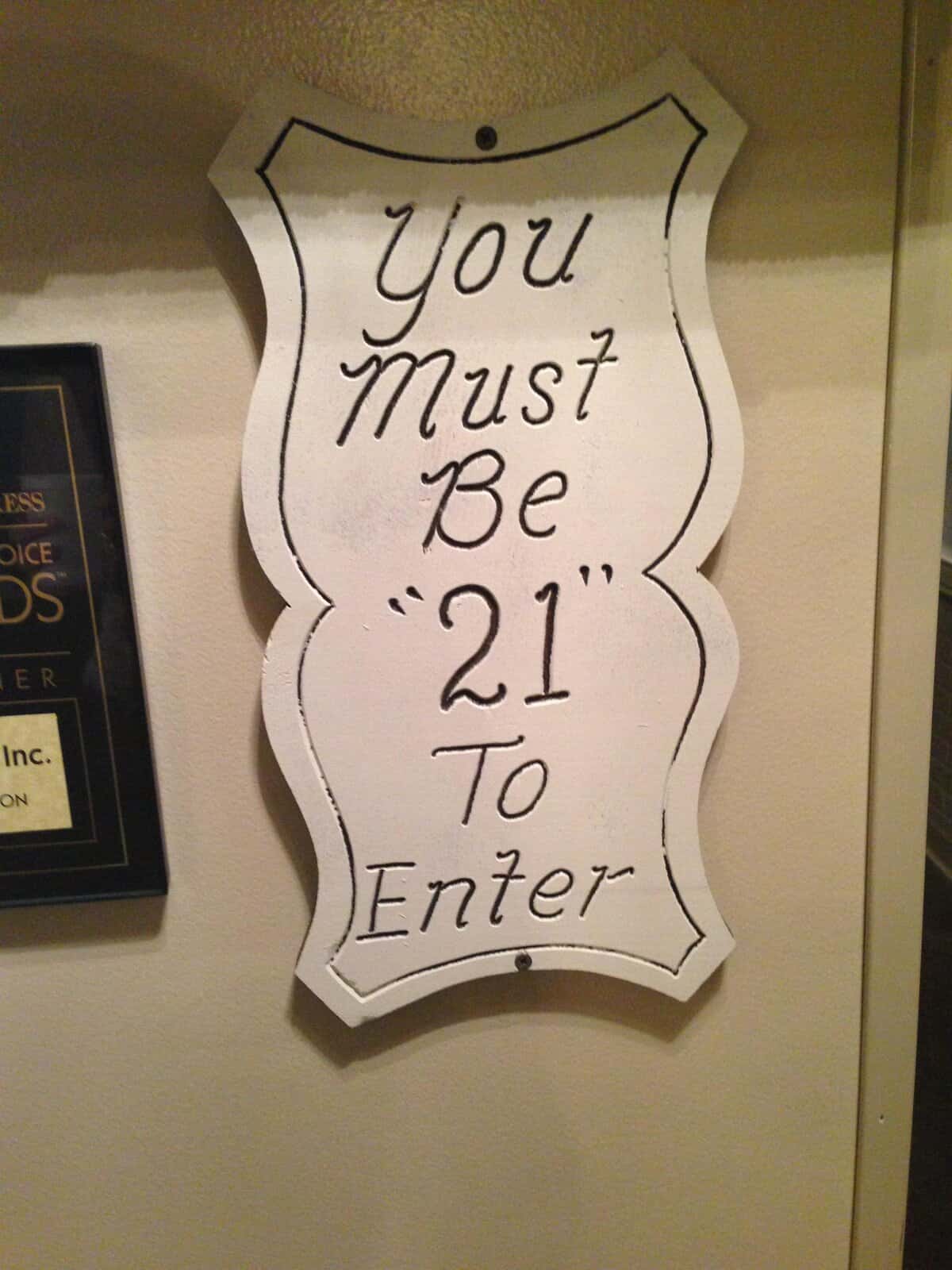 Decorative white sign stating you must be twenty-one in quotation marks to enter.