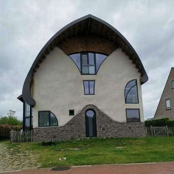 A uniquely shaped Belgian home with a curved roofline that resembles a large wide-brimmed hat.