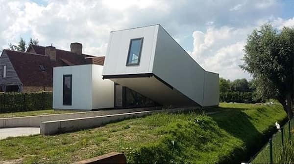 A modern Belgian house consisting of two white rectangular blocks, one leaning precariously against the other.