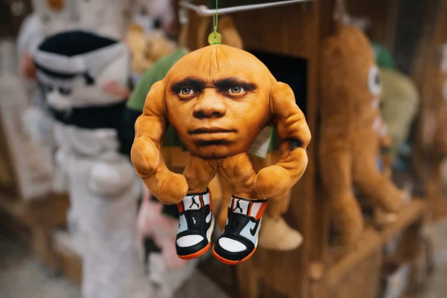 Strange orange-headed plush toy with muscular arms wearing sneakers for awful taste great execution collection.