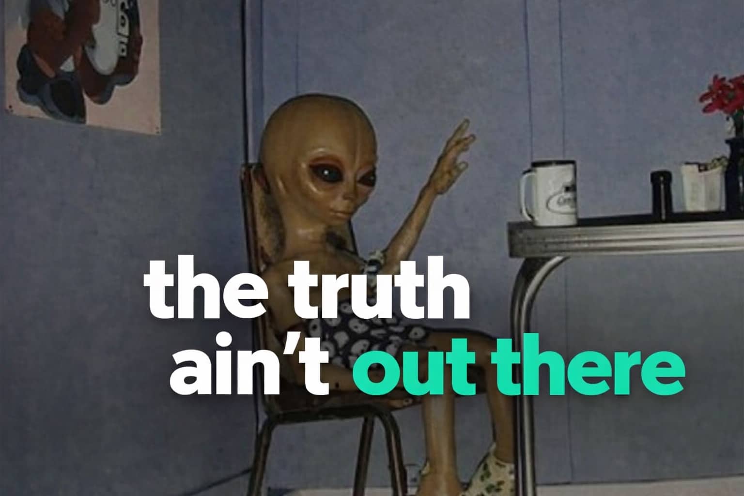 A classic grey alien sitting at a table with a coffee mug and text the truth ain't out there.