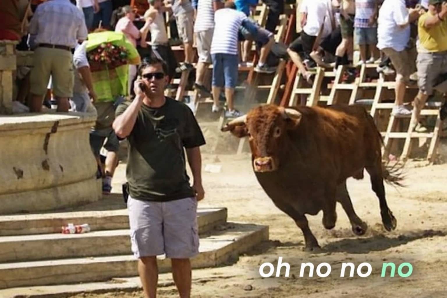A man on a phone unaware of a bull charging behind him with text oh no no no.