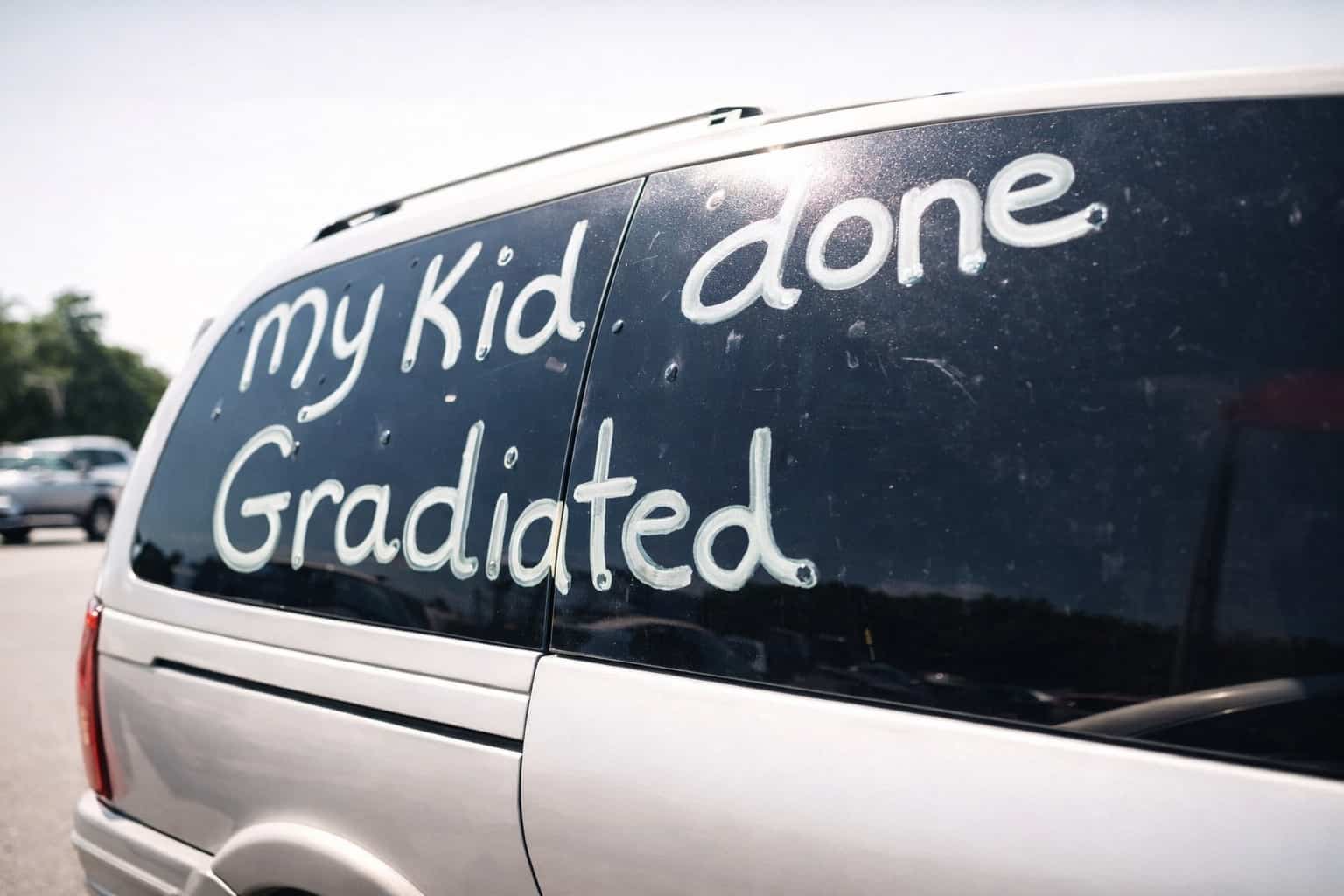 Van window with "my kid done Gradiated" written in white paint, showing funny spelling mistakes.