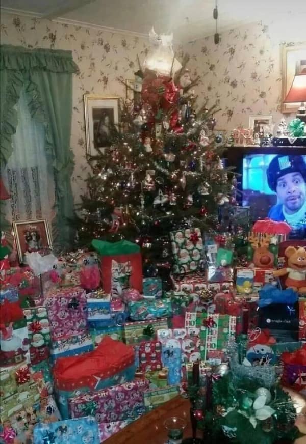 Pure 90s nostalgia captured in a messy, chaotic Christmas morning photo featuring a massively decorated tree, piles of wrapped presents, and an old tube TV playing a movie in this classic 90s meme.