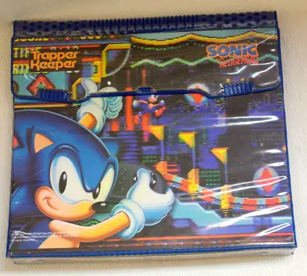 classic school supply featured in these 90s pictures showing a pristine, still-in-plastic Trapper Keeper binder with a bright, colorful Sonic the Hedgehog design on the cover.