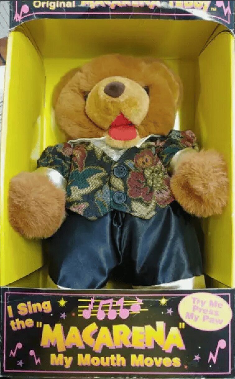 cursed entry in 90s pictures featuring the Macarena Teddy, a plush brown bear wearing a metallic floral vest and black shorts that actually danced and sang the viral hit song.