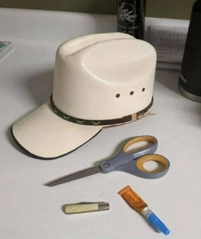 A standard white baseball cap awkwardly glued and folded to resemble a cowboy hat. A funny example of a hilariously bad DIY fashion project.