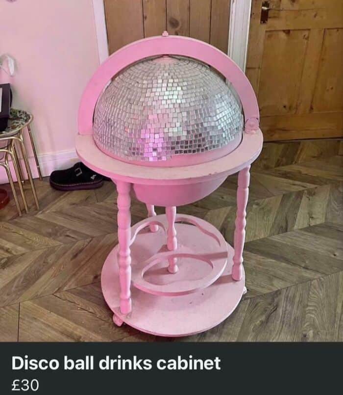 A horribly painted pink wooden globe stand transformed into a cheap disco ball drinks cabinet with visibly crooked mirror tiles. A classic aesthetic diy fail.