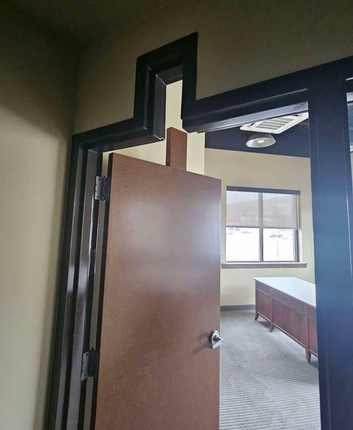 An architectural diy fail showing a custom zig-zag door frame paired with a standard rectangular door, leaving a massive awkward gap at the top of the office entryway.