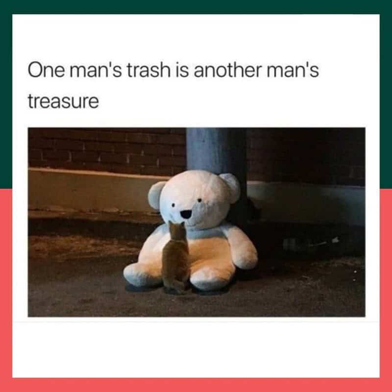 heartwarming yet slightly eerie funny animal meme showing a small cat looking up at a massive, discarded white teddy bear sitting under a streetlamp. The caption reads: "One man's trash is another man's treasure."