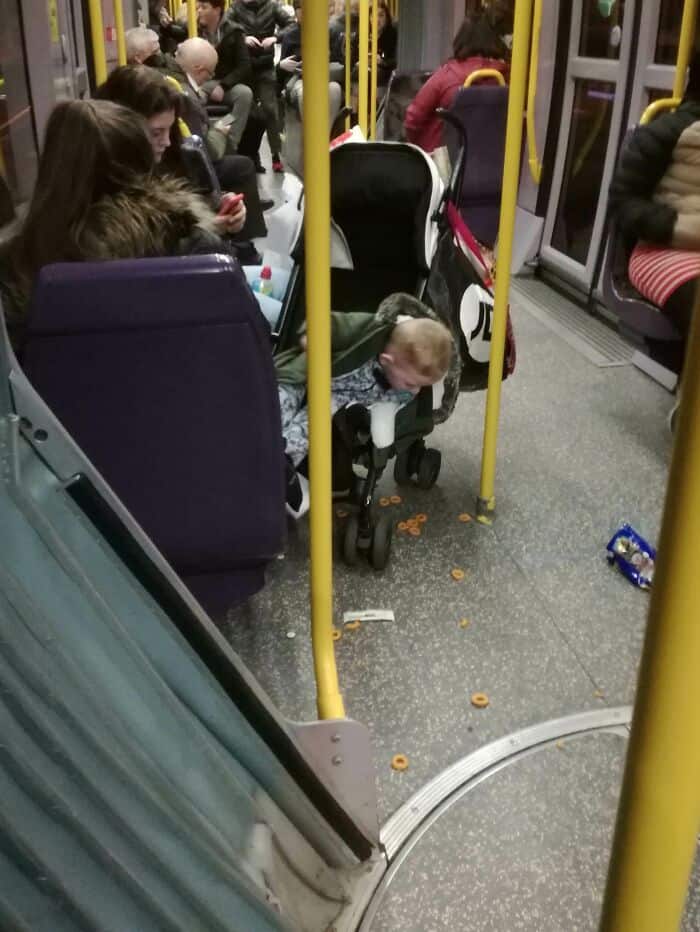 The chaotic aftermath of a "Cheerio explosion" around a stroller on a bus floor highlights the messy reality of traveling near annoying people on public transit