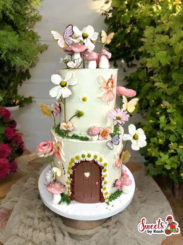 A magical fairy garden cake with a tiny door, mushrooms, butterflies, and delicate sugar flowers.