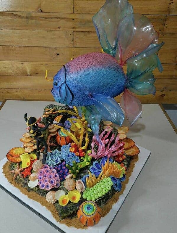 A stunning underwater scene cake featuring a large blue fish swimming over a colorful coral reef.