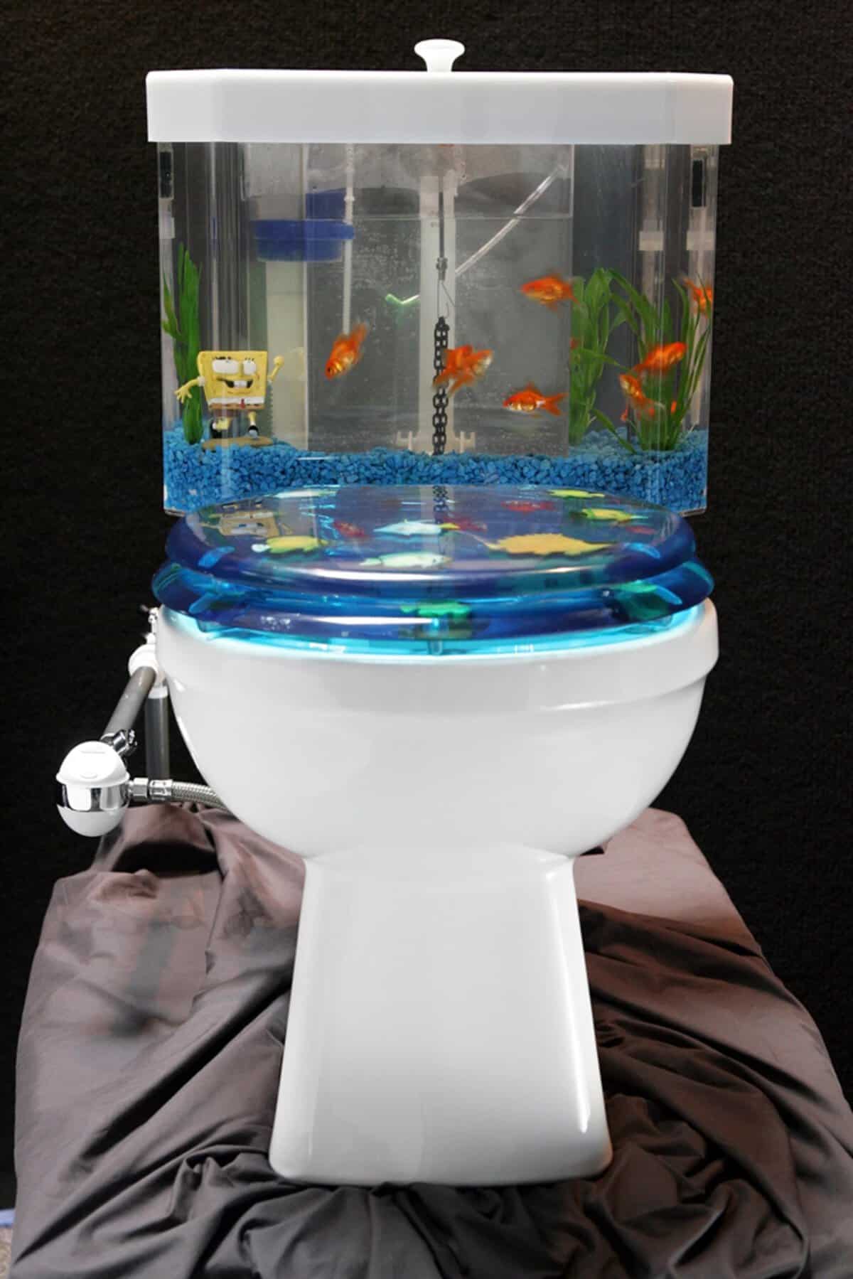 Novelty toilet with a transparent aquarium tank and blue fish-themed seat and lid.
