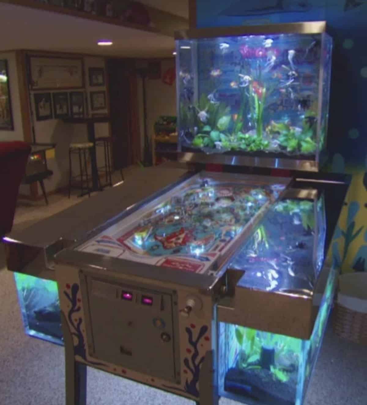 Vintage pinball machine repurposed into a multi-level aquarium with glowing lights and fish.