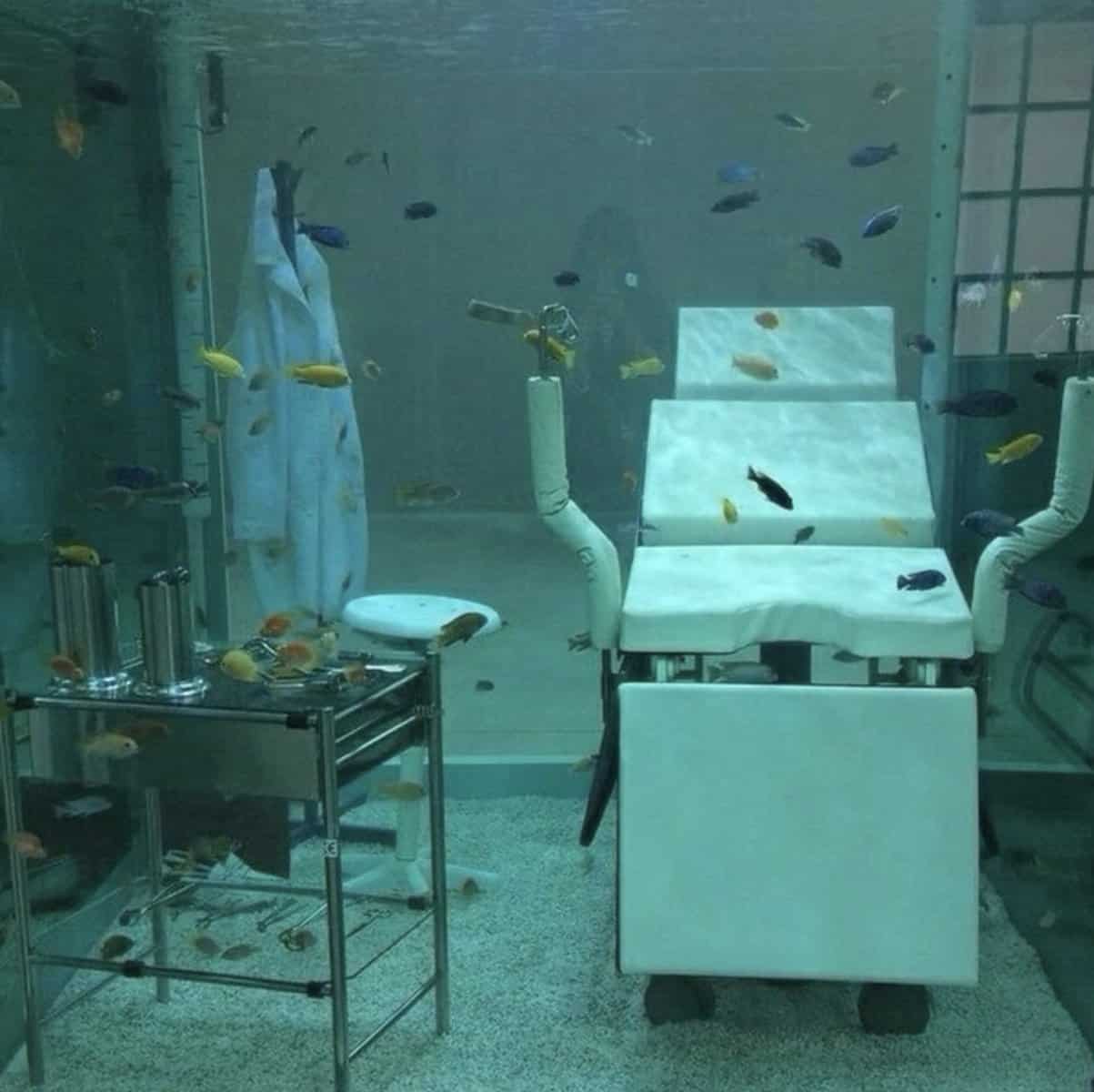 Surrealist art piece showing a full dentist office setup submerged inside a giant aquarium.