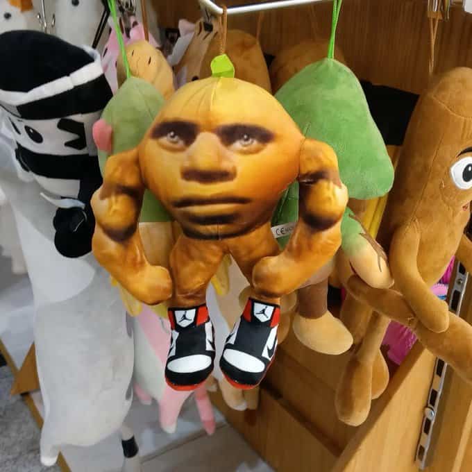 A bizarre plush toy featuring a muscular body with a realistic human face and sneakers.