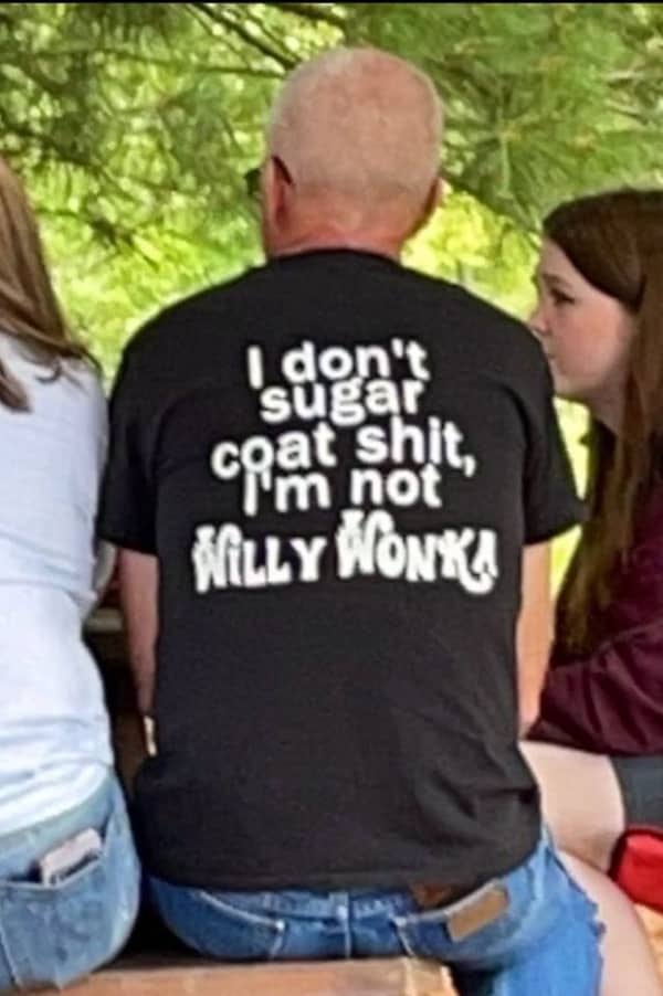 Back of a man's t-shirt reading "I don’t sugar coat shit, I’m not Willy Wonka" in bold font.