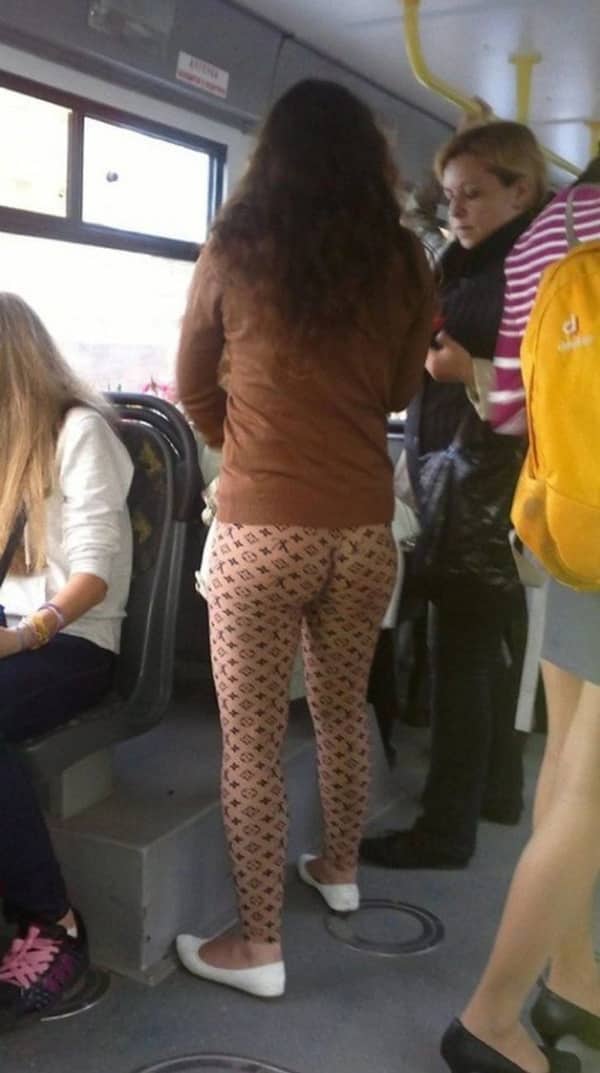 Woman on a bus wearing nude-colored leggings with a designer logo pattern that creates an unfortunate visual effect.