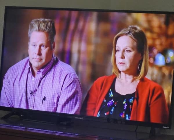A hilarious haircut fail captured on a television broadcast, showing a serious man with an impossibly stiff, rectangular flat-top block of blonde hair standing straight up like a paintbrush.