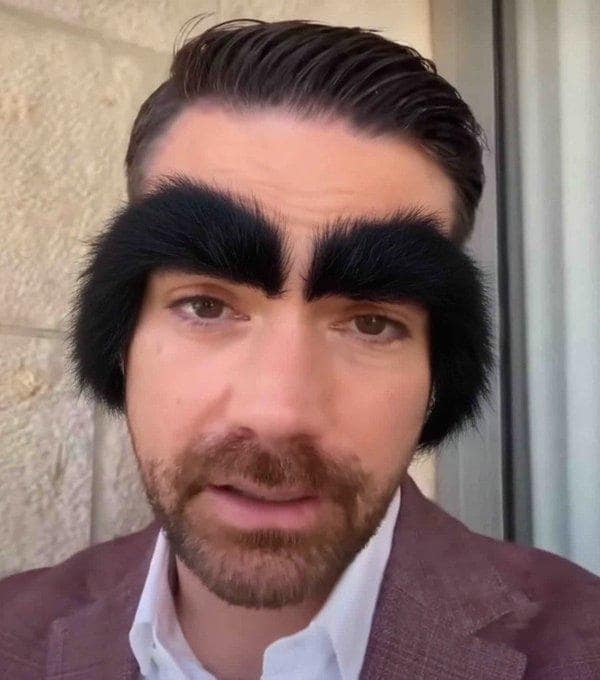 hilarious close-up Ben Shapiro eyebrows meme where his facial hair has been digitally altered to feature massive, unnaturally bushy black eyebrows that resemble hairy caterpillars, highlighting the internet's obsession with his recent groomed appearance