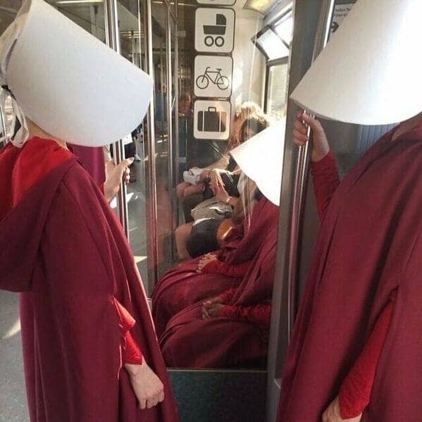 Multiple people dressed in Handmaid's Tale costumes riding the Berlin subway together.