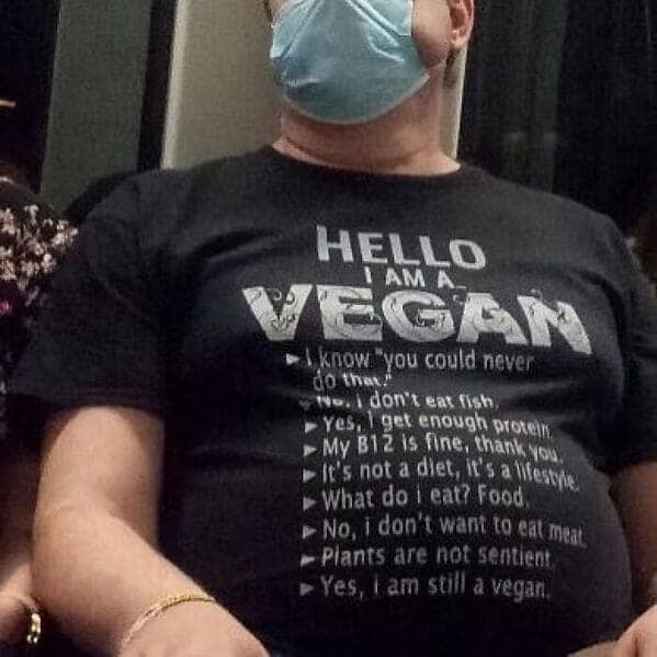 Passenger wearing a black t-shirt with a long list of vegan FAQ responses.
