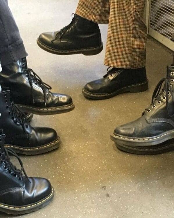 Group of passengers all wearing identical black Dr. Martens boots on the train.