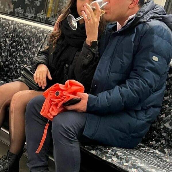 Couple enjoying a sophisticated moment drinking white wine from real glasses on the subway.