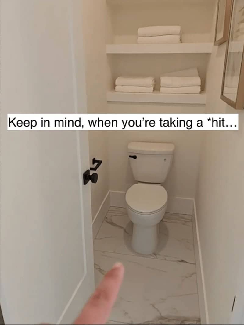 Small toilet room with marble tile and open shelving located directly next to a bedroom.