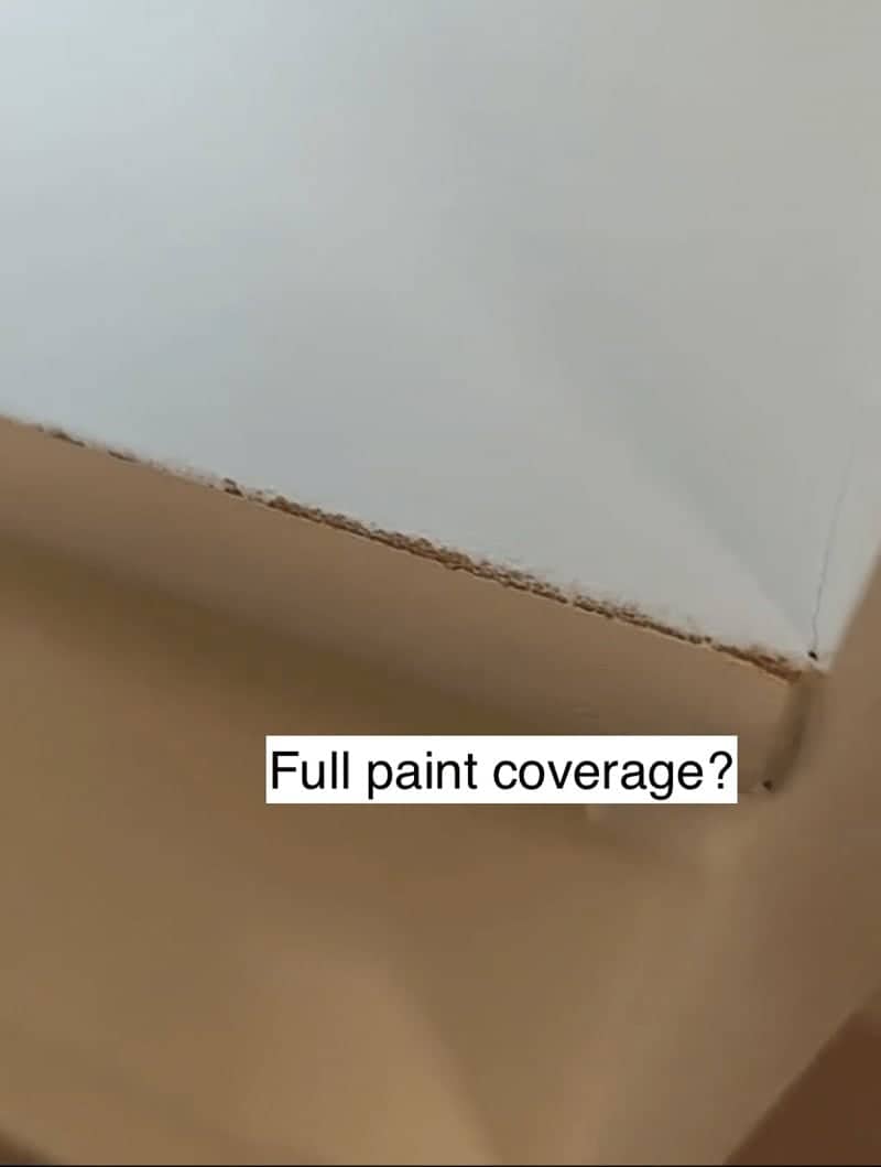 Close up of a wall edge with visible unfinished wood and jagged messy paint coverage.