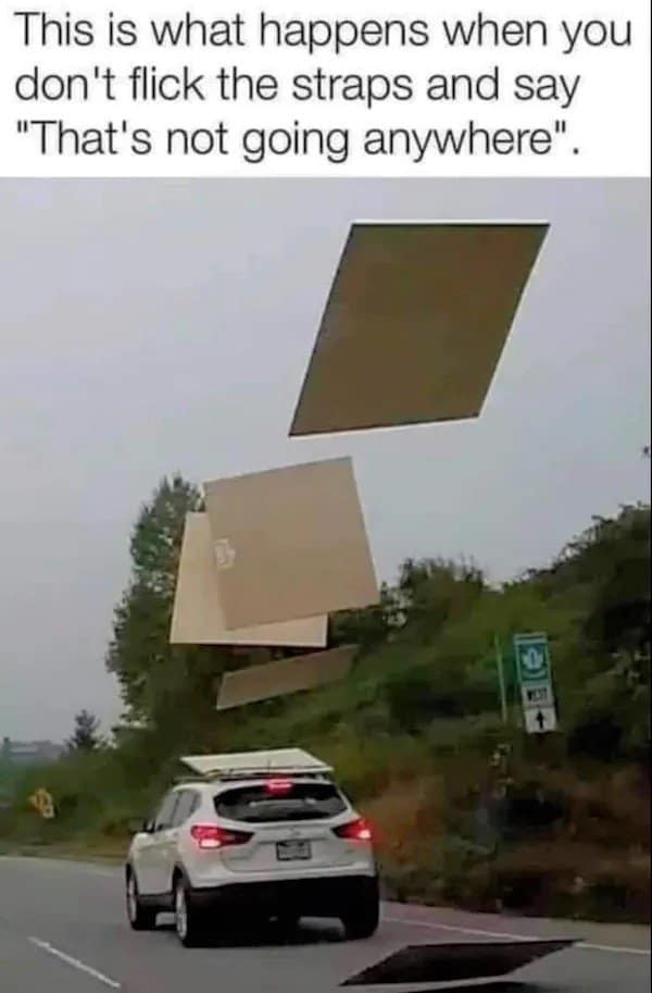 An old meme capturing the exact moment four large sheets of plywood fly off the roof of a white SUV on the highway. The caption mocks a failure of DIY safety: "This is what happens when you don't flick the straps and say 'That's not going anywhere'."