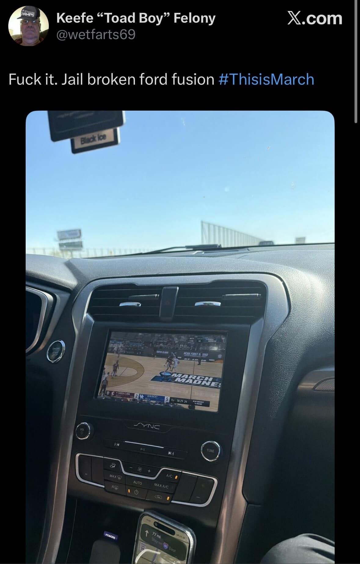 A "chaotic energy" classic meme tweet from user @wetfarts69. It shows the interior of a Ford Fusion with a jailbroken infotainment screen being used to live-stream a March Madness basketball game while driving, captioned simply: "#ThisisMarch."
