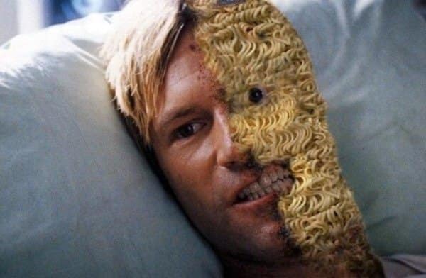 A bizarre old meme edit of the character Two-Face from The Dark Knight, where the scarred, burnt half of his face has been replaced with a textured block of dry, uncooked ramen noodles.