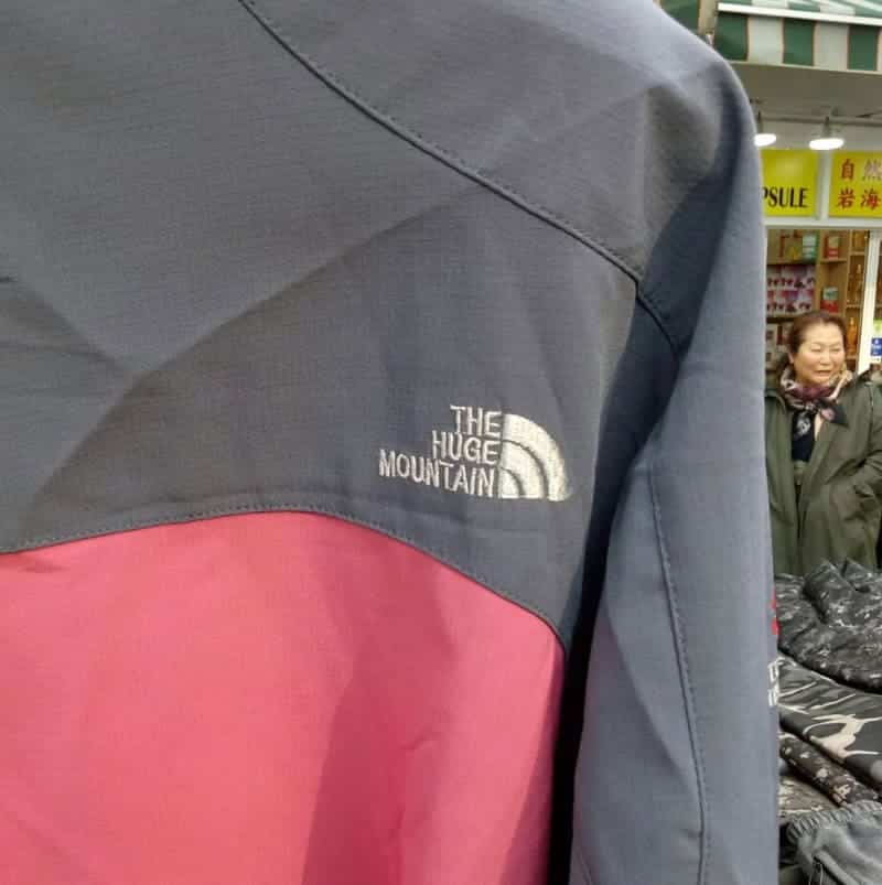 Outdoor jacket featuring an embroidered logo that says The Huge Mountain instead of The North Face.