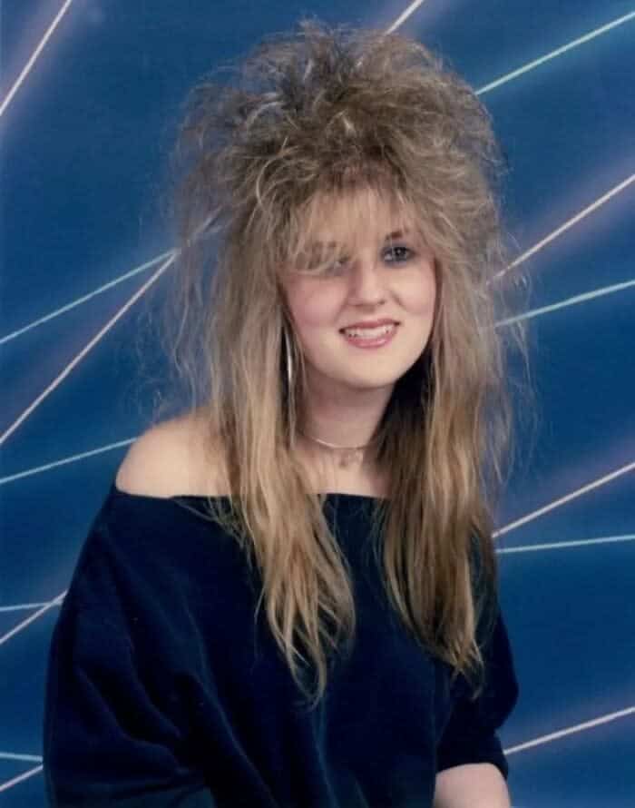 1980s portrait of a woman with a crimped, messy-chic hairstyle featuring significant height and volume.