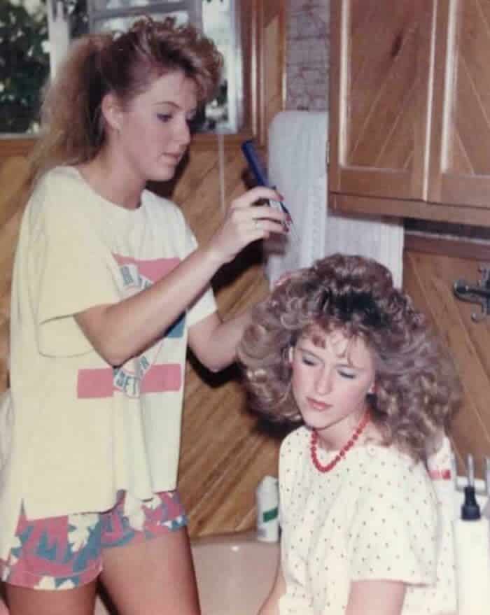 Candid photo of a girl having her hair teased and sprayed into an 80s style.