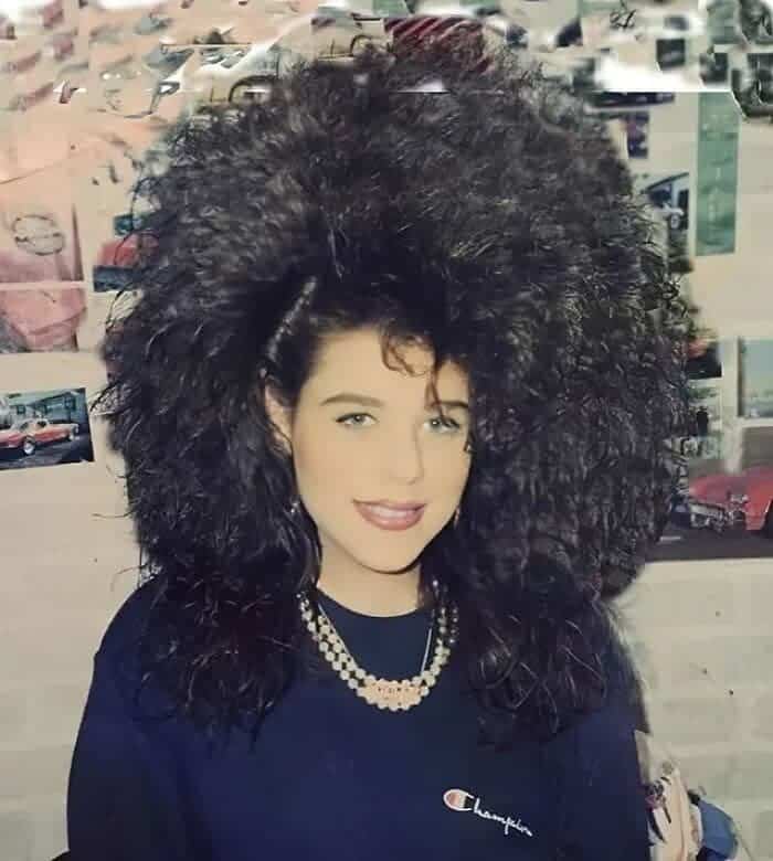 Woman with jet black hair styled into an enormous, spherical cloud of tight curls.