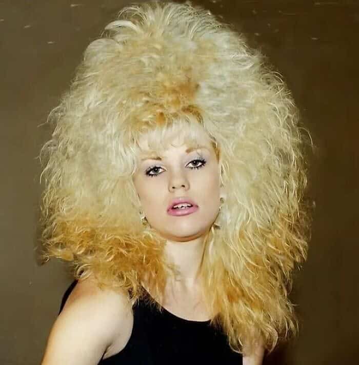 Studio photo of a woman with platinum blonde hair teased into a massive, rounded bouffant.