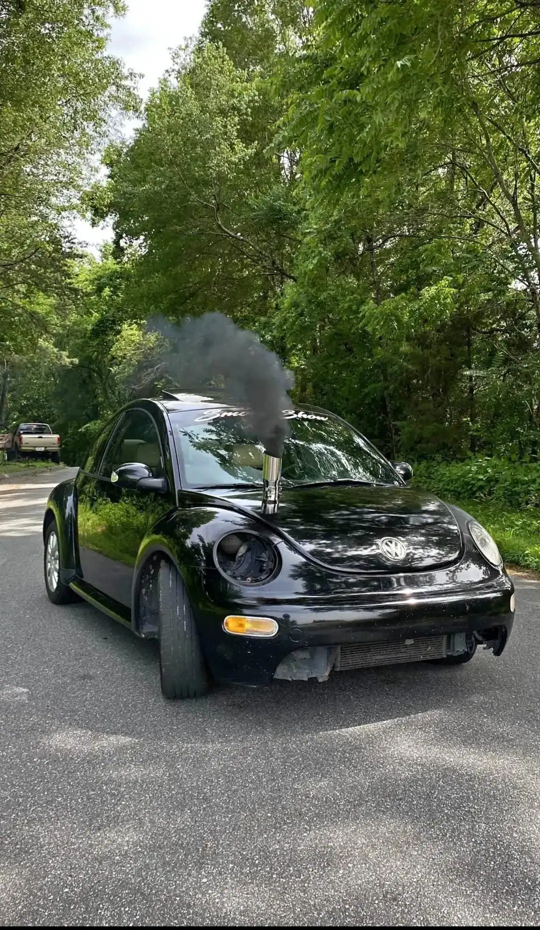 Black Volkswagen Beetle with a large vertical exhaust stack on the hood emitting thick black smoke.