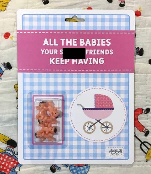 A satirical death by toys product titled "ALL THE BABIES YOUR S[CENSORED] FRIENDS KEEP HAVING". The packaging features a cluster of tiny, tan plastic babies inside the bubble next to a pink-and-blue checkered background with a stroller icon.