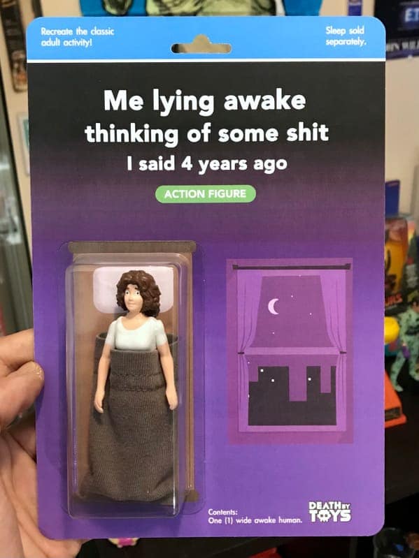 A relatable funny fake action figure titled "Me lying awake thinking of some shit I said 4 years ago". The figure depicts a woman with wide eyes tucked into a brown fabric "bed," with a nighttime window scene on the card and the note: "Sleep sold separately".