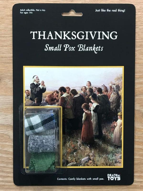 funny fake action figure titled "THANKSGIVING Small Pox Blankets." The product contains three small, folded pieces of plaid and green fabric, packaged against a classic painting of Pilgrims and Native Americans.