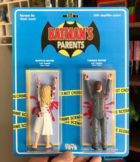 death by toys two-pack titled "BATMAN'S PARENTS." The figures of Martha and Thomas Wayne are shown from the back, dressed in formal wear and pinned against a crime scene backdrop covered in dramatic red blood splatters.