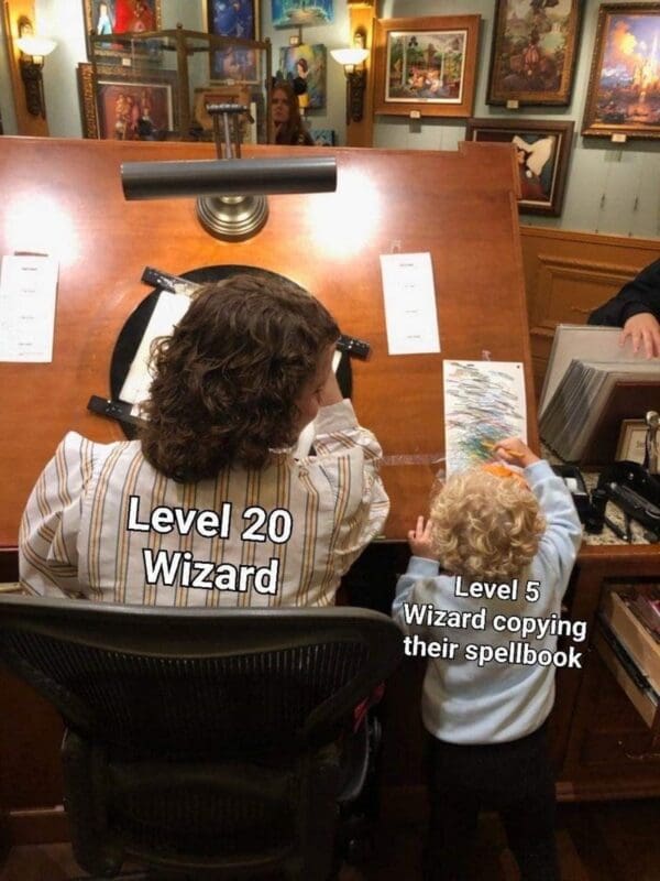 A dnd meme showing a woman labeled "Level 20 Wizard" working professionally at an art desk, while a toddler labeled "Level 5 Wizard copying their spellbook" excitedly scribbles on a piece of paper beside her.
