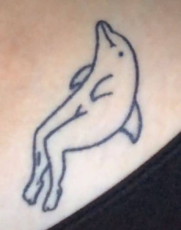 Humorous and bizarre tattoo of a dolphin with a pair of human legs.