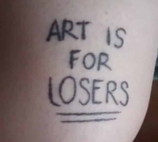 Ironic tattoo featuring the handwritten phrase art is for losers in plain black ink.