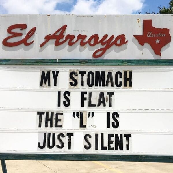 A clever spelling joke on an el arroyo sign proudly announcing my stomach is flat, the L is just silent, creating a top tier self-deprecating funny restaurant sign.