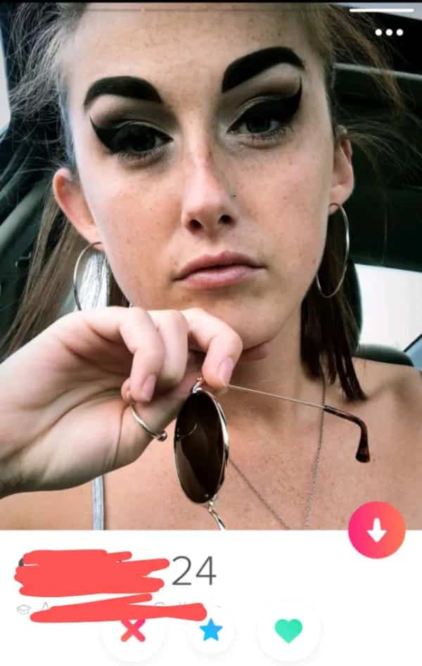 Tinder profile screenshot of a woman with massive thick arched black blocky eyebrows.